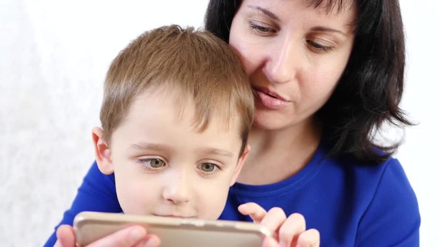 Portrait of a woman and child. Happy family: Mom and son hold a smartphone and play with the application for children in the Internet. The generation of millennia and Z.