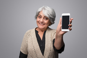 Smiling elderly woman showing smartphone