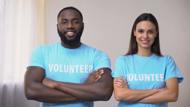 Mixed-race volunteers standing with hands crossed in rehabilitation center, help
