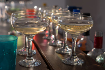 Glasses of champagne lined up on a bar. Bokeh in background.