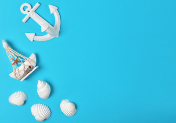 Top view of anchor, seashells and sailing boat decoration on bright blue background, summer concept