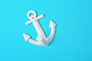 White anchor on bright blue background, flat lay