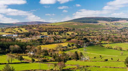 Fototapeta na wymiar Irish countryside landscape as seen from above, with green meadows and forest covered hills on a sunny spring morning. View from the top of Barnaslingan Hill, Co. Dublin, Ireland.