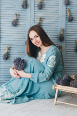 .Beautiful young woman sitting with lavender against the blue wall.