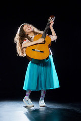 Fototapeta na wymiar Little girl with curly hair plays the guitar