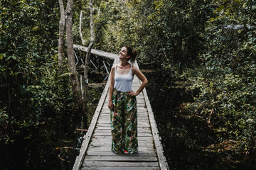 .Young woman enjoying the forest jungle on the island of Borneo, Indonesia. Enjoying a moment of peace on a wooden path prepared to see wildlife of the rainforest. Travel Photography