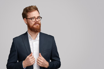 Confident red haired businessman adjusting jacket