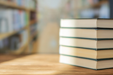 Book stack on the desk in the library room under sunrays