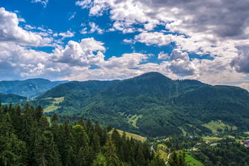 Fototapeta na wymiar Beautiful mountain scenery with clouds, forests and blue sky in Transylvania, Romania, Eastern Europe. Remote place, vacation, relaxing, fresh air.