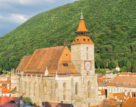 Famous medieval Black Church built in gothic style with Tampa mountain in the background and Brasov historic old town, Transylvania, Romania, Eastern Europe. Landmark building in the city center. 