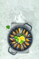 Seafood mussels with lemon and parsley in black metal pan