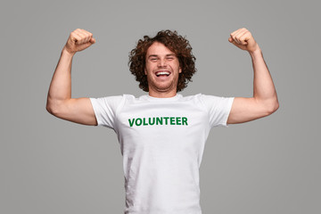 Strong volunteer smiling and flexing muscles