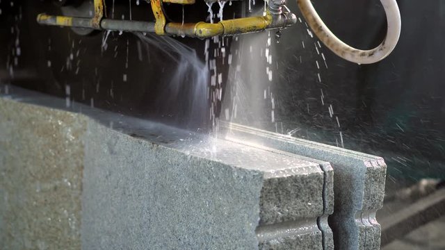 Bridge saw machines cutting granite block in slow motion
