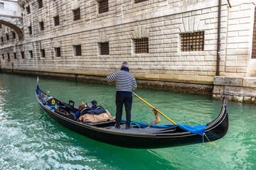 Fototapeta na wymiar Traditional canal street with gondolier in Venice, Italy
