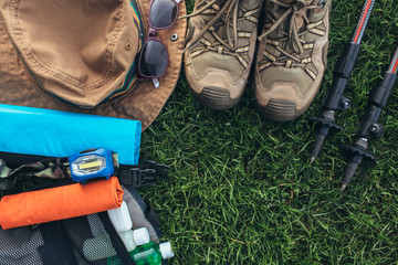 Set of equipment for hiking and travel on green grass with copy space . Items include trekking...