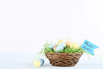 Colorful eggs in basket with text Happy Easter on white background