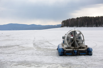 Hovercraft transporter on the ice of river in winter day