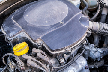 Close up view of an used and dirty car engine. Old auto parts under the hood. Dust accumulation on the components. 