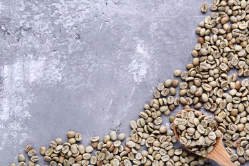 Green coffee beans with spoon on grey wooden table