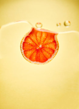 Fruit slice in water against yellow background