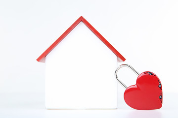 Wooden house model with padlock in shape of heart isolated on white background