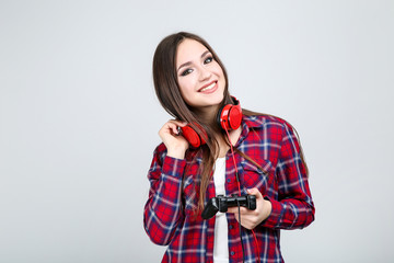 Beautiful girl with joystick and headphones on grey background