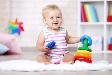 Baby girl sitting on white carpet with toy