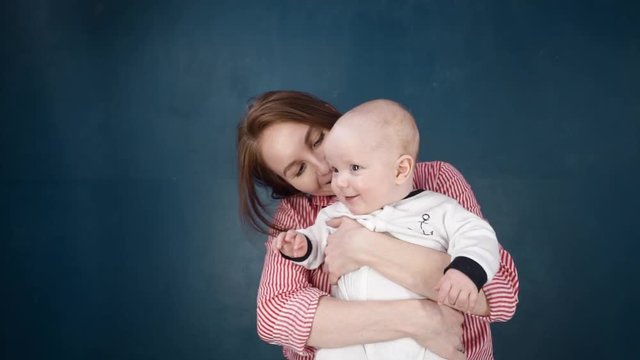 Happy Caucasian people and children. A young mother holds a newborn baby in the air in her arms talking to him. Mother smiles and laughs a boy. Fun for a woman, cute boy in her arms. Slow motion. HD