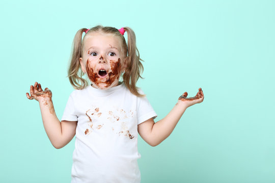 Happy little girl in chocolate on mint background
