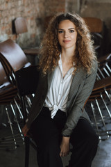 Young girl in a jacket sitting on a wooden chair