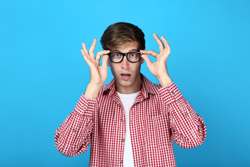 Beautiful young man with glasses on blue background
