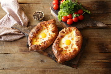 Two Khachapuri Adjara traditional Georgian dishes. Baked bread stuffed with cheese and eggs. With copy space for text. Flat lay. Top view. 