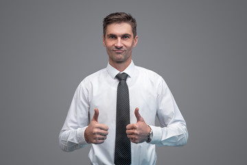 Confident businessman gesturing thumb ups