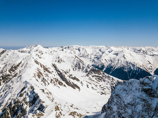 Fototapeta na wymiar winter landscape with the mountain peaks covered by snow and clouds. aerial view by drone. romanian mountains, Negoiu peak, Fagaras Mountains