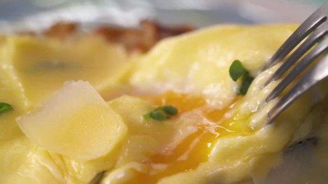 Slicing a poached egg with a knife on eggs benedict. Haute cuisine concept