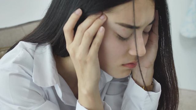 Asian woman feeling stress from work in the office.Tired business woman at workplace in office holding his head on hands feel headache.