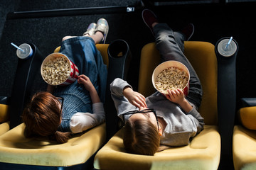 overhead view of friends eating popcorn and watching movie in cinema