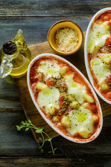 Italian potato dumplings gnocchi alla sorrentina with mozzarella cheese, baked in the oven with tomato sauce and herbs. Served with parmesan and spices. Classic healthy vegetarian cuisine