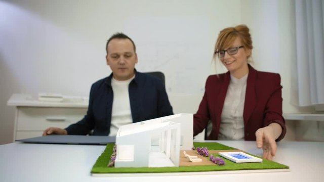 Two architects playing with a model house in office