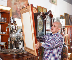 Ordinary male carefully examining antiques