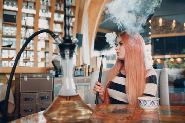 Fototapeta na wymiar Young beautiful female smoking hookah. Smoke shisha hookah concept.