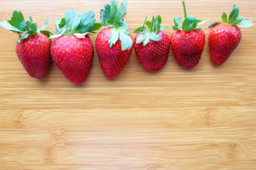 Fresh harvest strawberries with green leaf abreast on wooden table ,side view .Strawberry fruit.