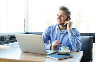 Stylish young man calling by the phone to solve business problems. Online consultation by phone. Freelancer discussing the development and planning of his online project. Outsourcing. Mobile services.