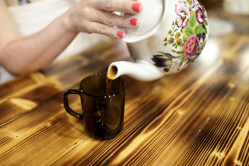 Woman pouring tea from ceramic teapot
