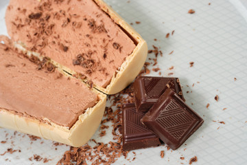 Chocolate ice cream in a waffle with chocolate chips on a white plate.