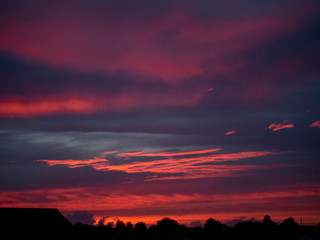 Dramatic sunset sky, Rich red and blue tones.Town houses silhouettes on the horizon.