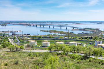 Railway bridge across the Volga river against the background of green vegetation and sky covered with clouds, Saratov, Russia