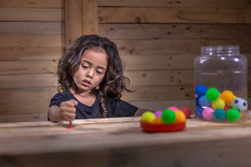 a long hair boy wear black shirt playing with colorful balls in wooden room