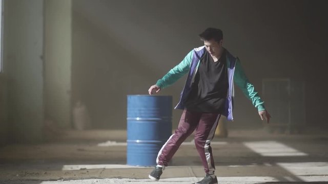 Sports young hip-hop dancer dancing near the barrel in an abandoned building in the fog. Hip hop culture. Rehearsal. Contemporary.