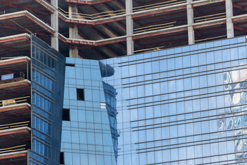 high-rise construction crane with a long arrow of yellow color against the blue sky over a new...